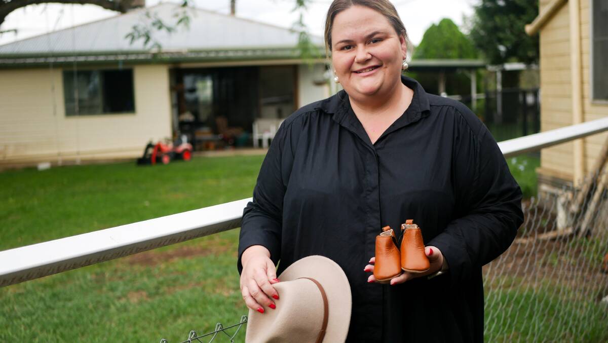 Casey holds an example of the footwear and hats she sells through her small business, which she runs from her family's property. 