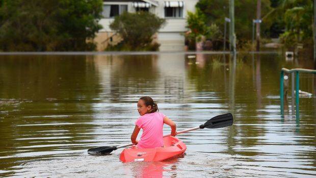 Eight-years old Maleah Jones canoes up flooded Bright street to her home in Lismore. Photo: Kate Geraghty
