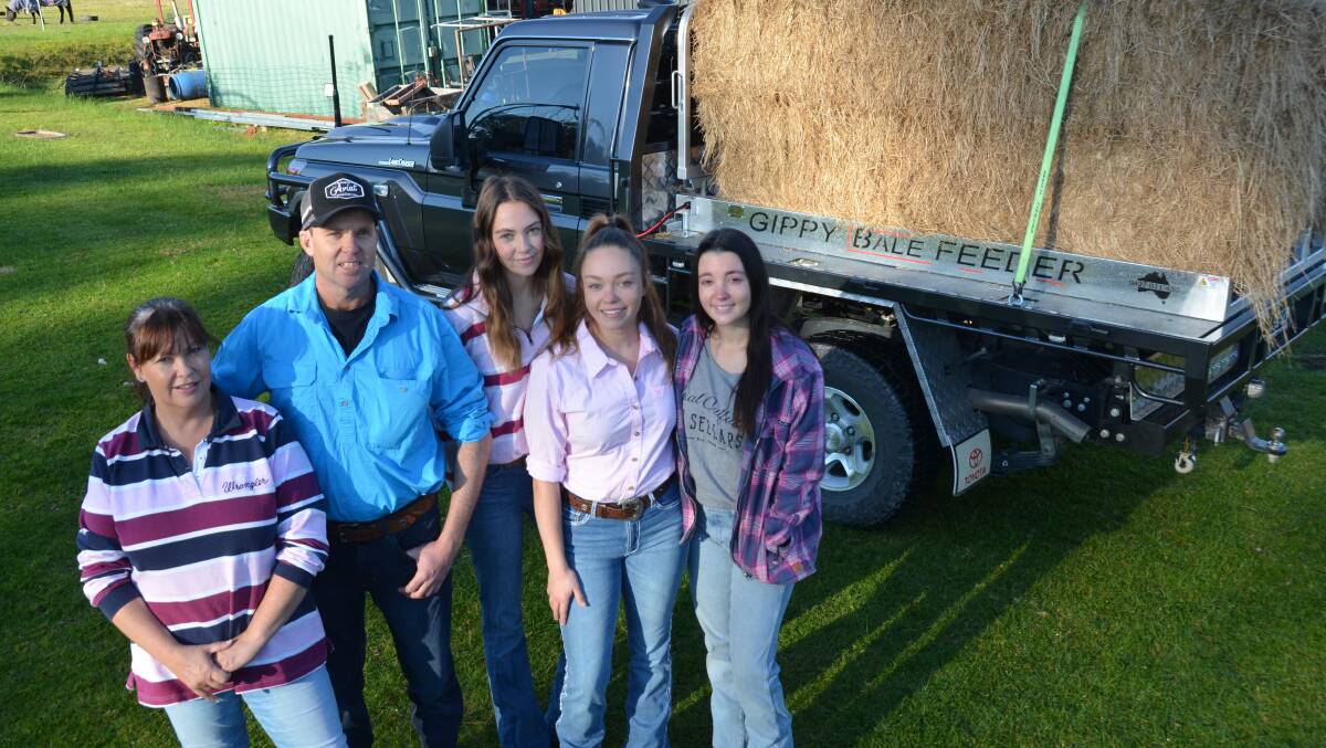 Kim and Matt Higgins, Briagolong, and their daughters Emma, Mel and Sarah stand beside the Gippy Bale Feeder their father developed after a near-death experience. Pictures by Bryce Eishold
